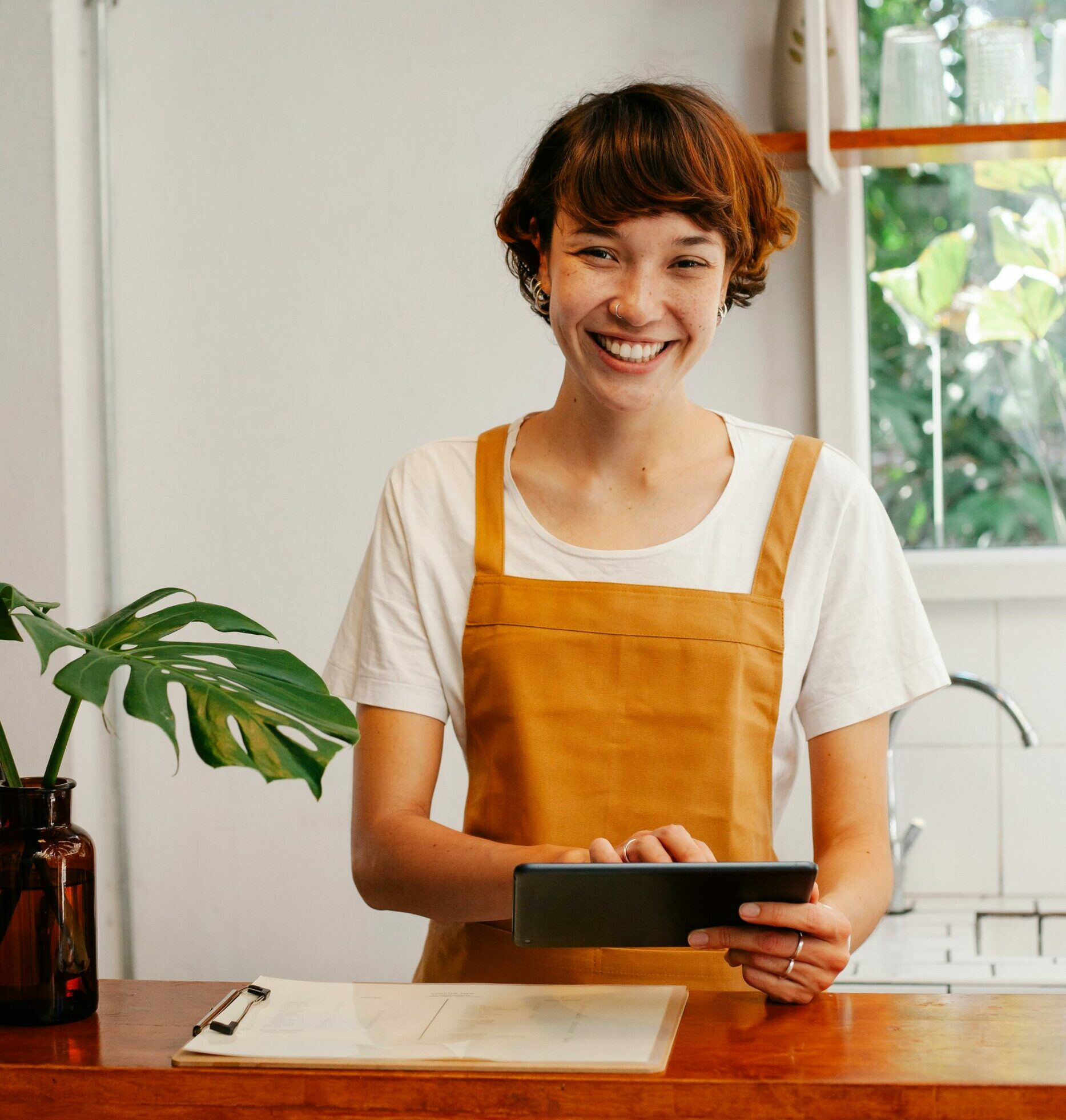 Serveuse de restaurant qui prend la commande sur une tablette de commande tactile en souriant