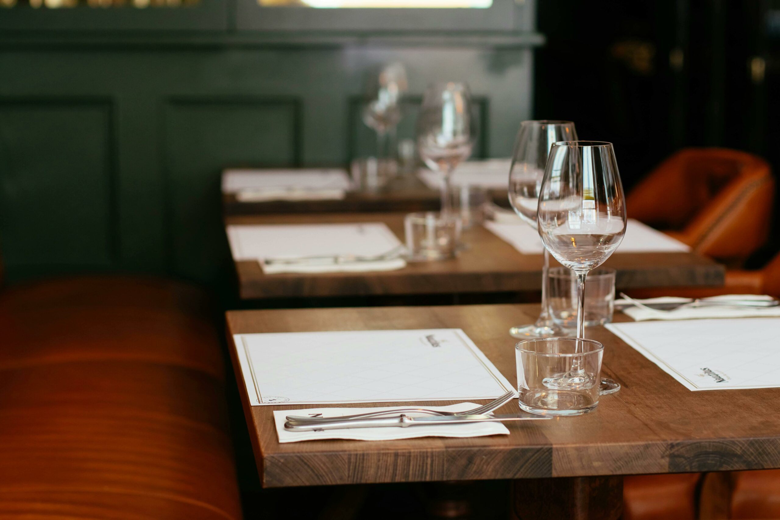 Cette photo montre une table dressée à l'intérieur d'un restaurant. On y voit des couverts et des verres.