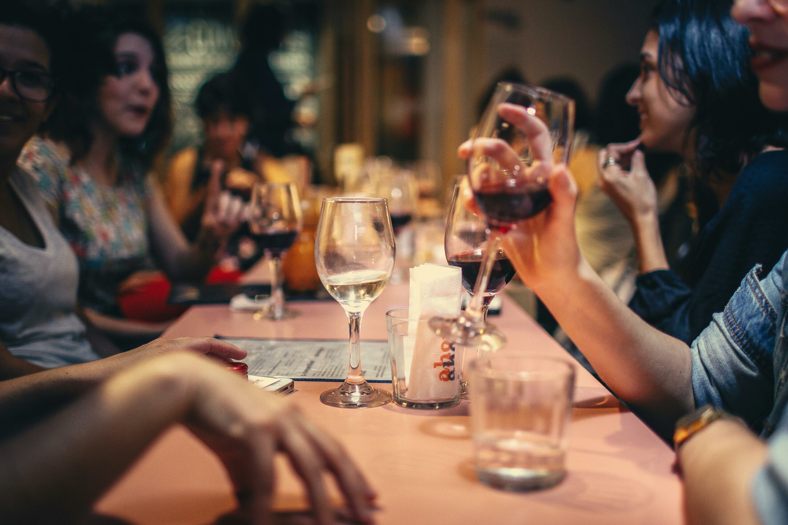 Personnes à table dans un restaurant discutant autour d'un verre de vin