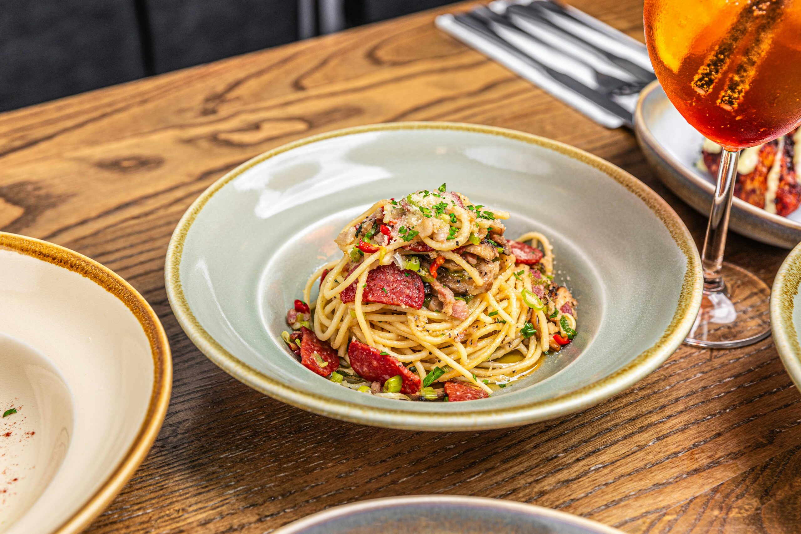 La photo montre une assiette de spaghettis et un cocktail sur une table de restaurant.