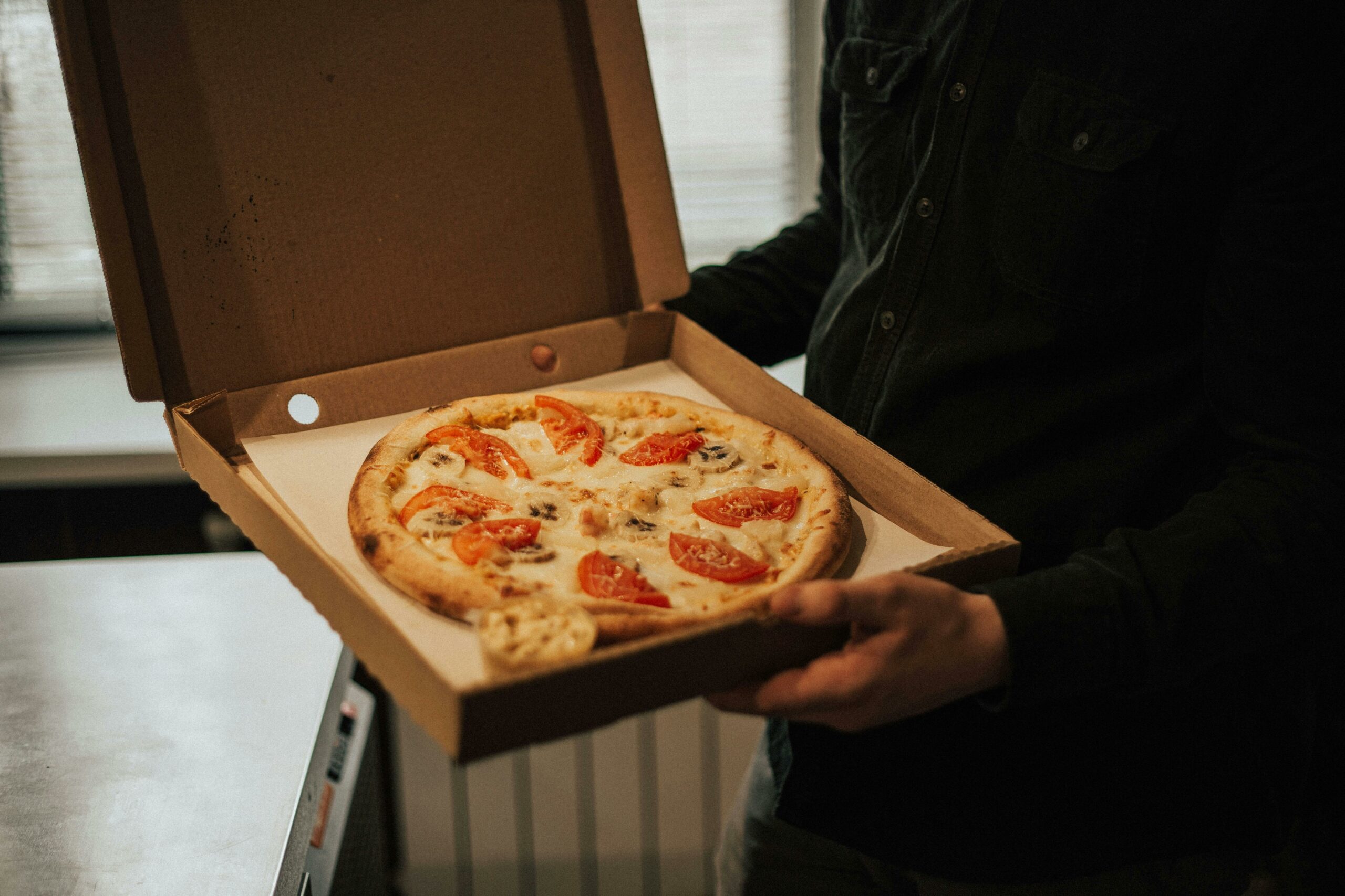 cuisinier d’une dark kitchen préparant une pizza pour livraison