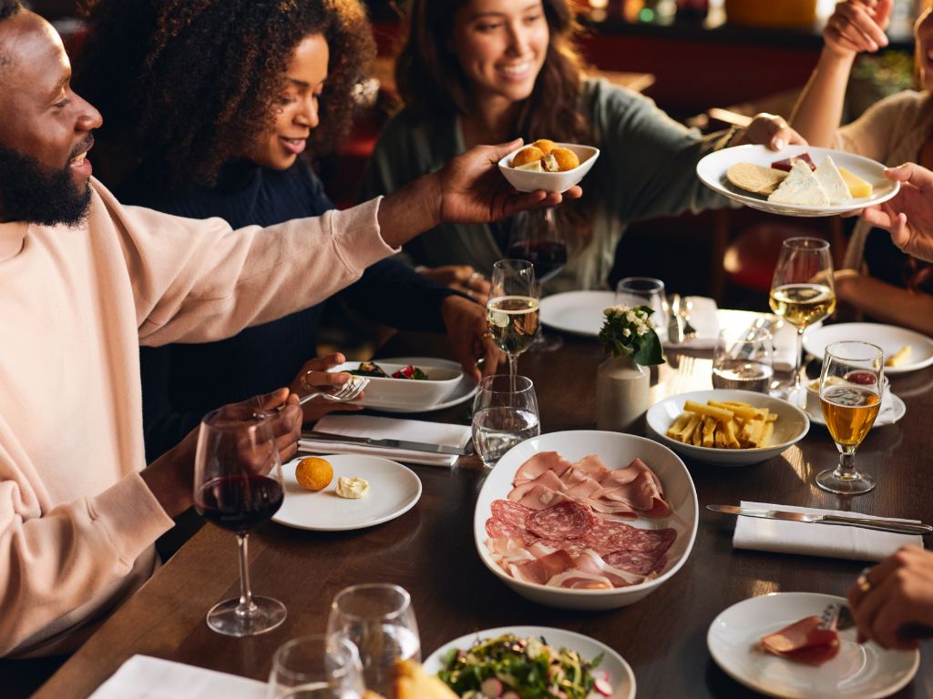 La photo montre un groupe de personnes assis à la table d’un restaurant en train de partager des plats.